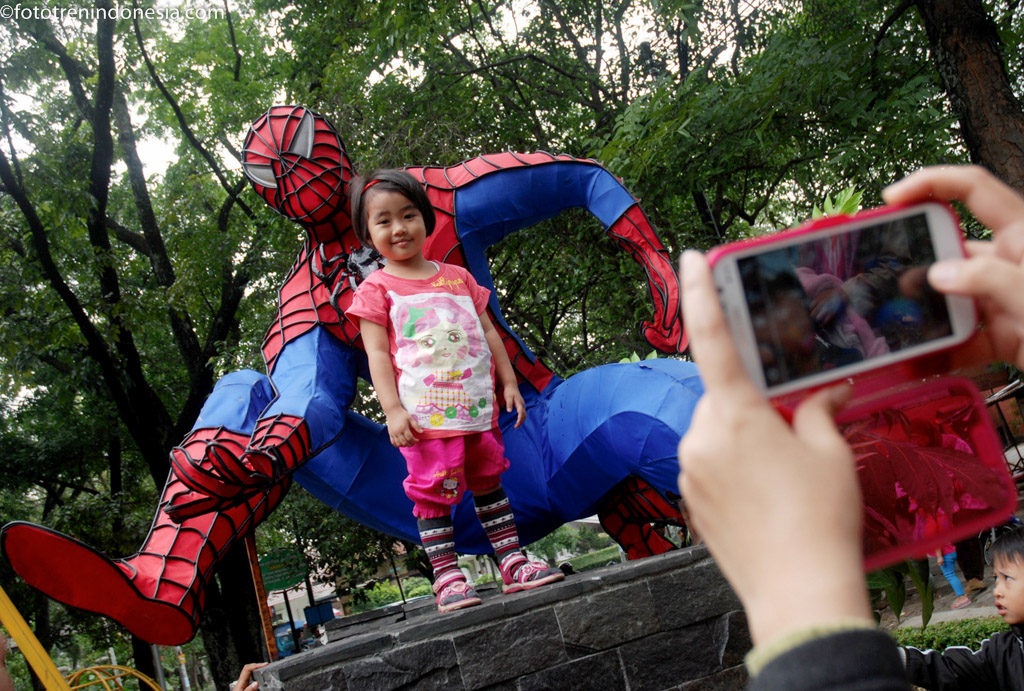 Seorang anak berpose bersama replika tokoh kartun Spiderman di kawasan Taman Superhero, Bandung, Jawa Barat, Minggu (18/1)